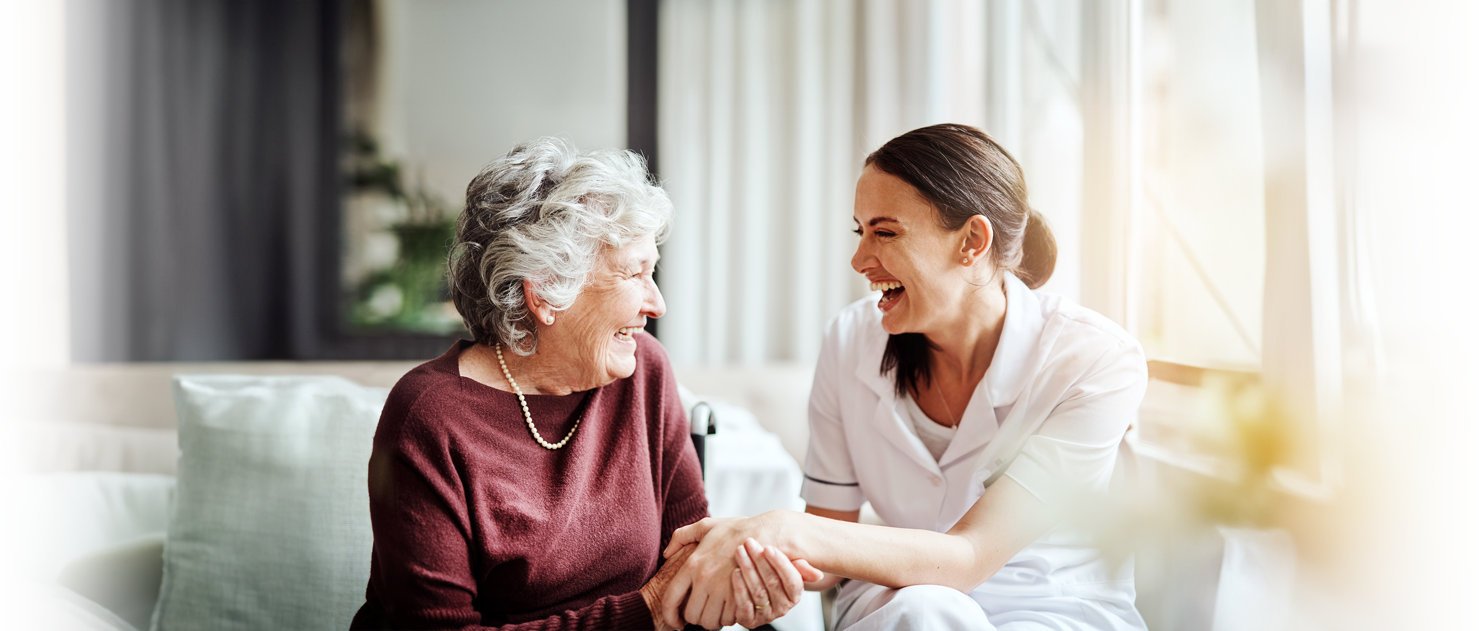 An older woman receiving home care in Silver Spring laughs with her caregiver by her side.