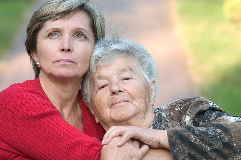 A woman hugs her elderly mother as she works at understanding Alzheimer’s and wonders if she will also get the disease.