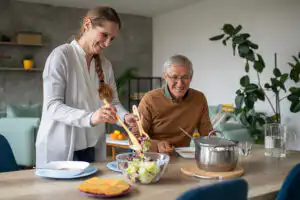 A woman prepares a meal for her elderly father as she helps him overcome senior nutrition challenges.