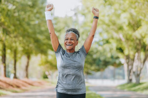 An older woman celebrates after an outdoor workout, because daily exercise is one of the SMART goals for seniors she committed to this year.