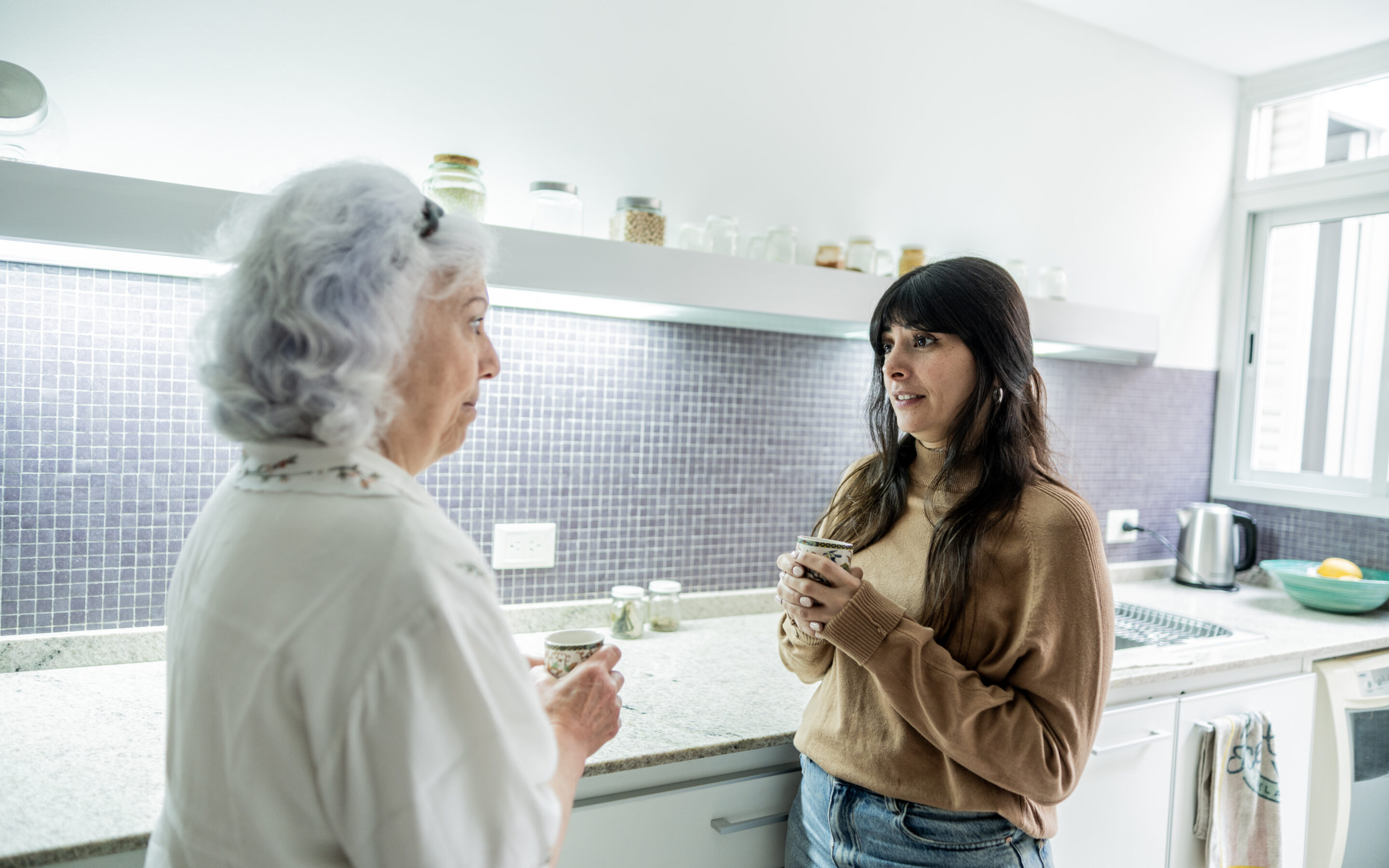 A woman uses communication strategies for caregivers and seniors as she has a conversation with her elderly mother.