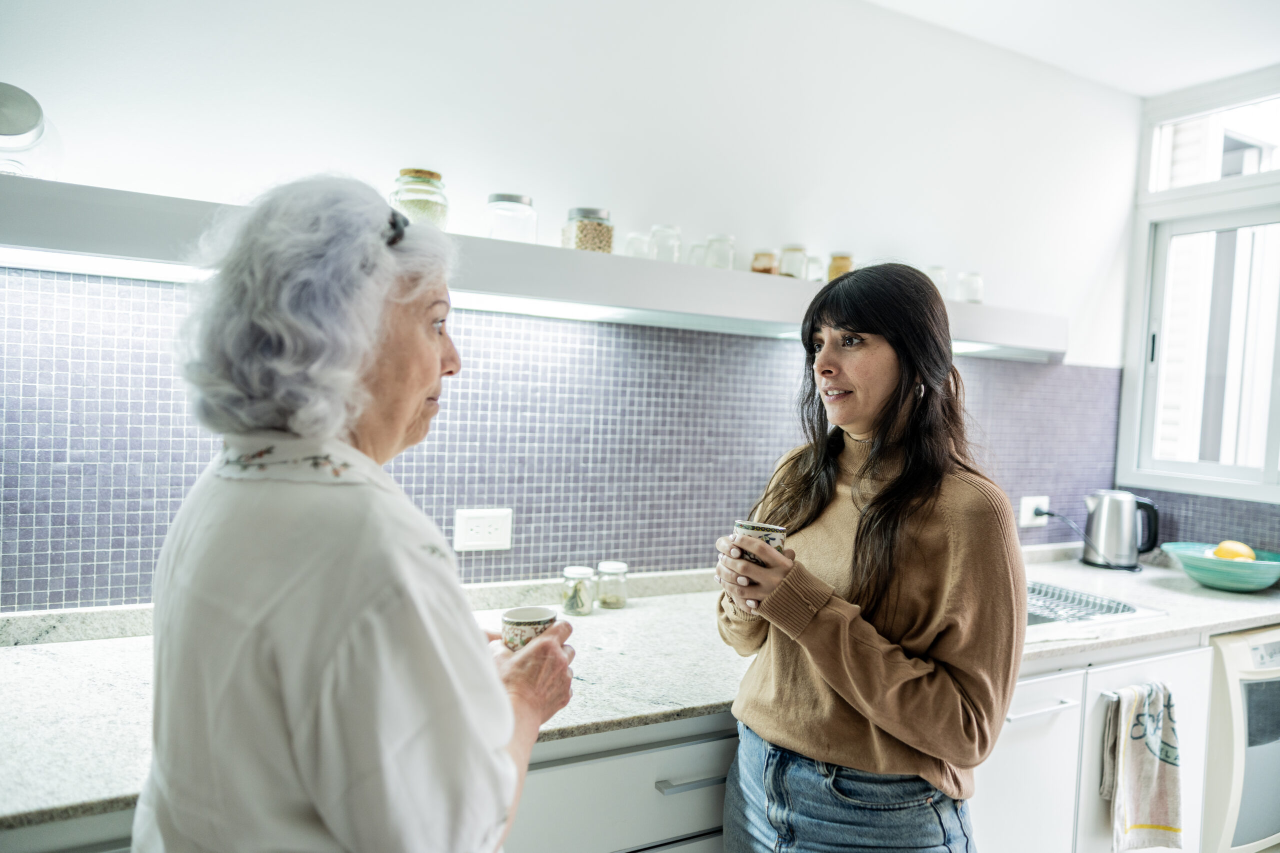 A woman uses communication strategies for caregivers and seniors as she has a conversation with her elderly mother.