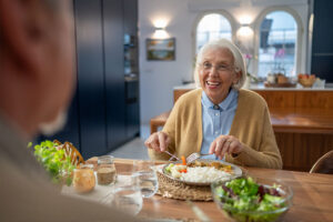 A senior woman follows elderly nutrition tips as she eats a healthy dinner.