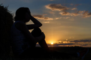 A woman reflects on coping with caregiver guilt alone in a peaceful setting.