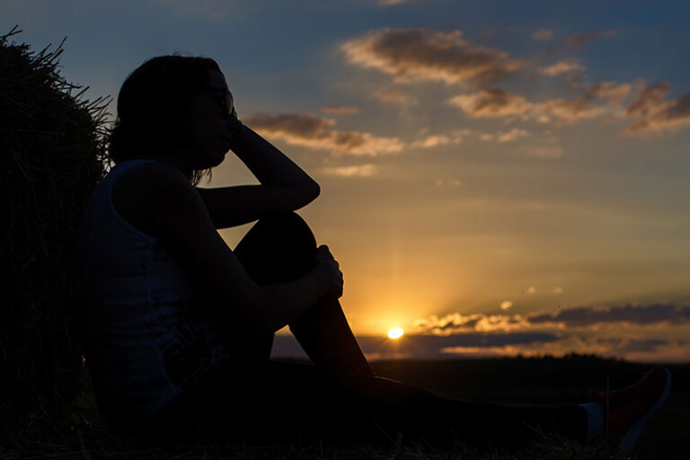 A woman reflects on coping with caregiver guilt alone in a peaceful setting.